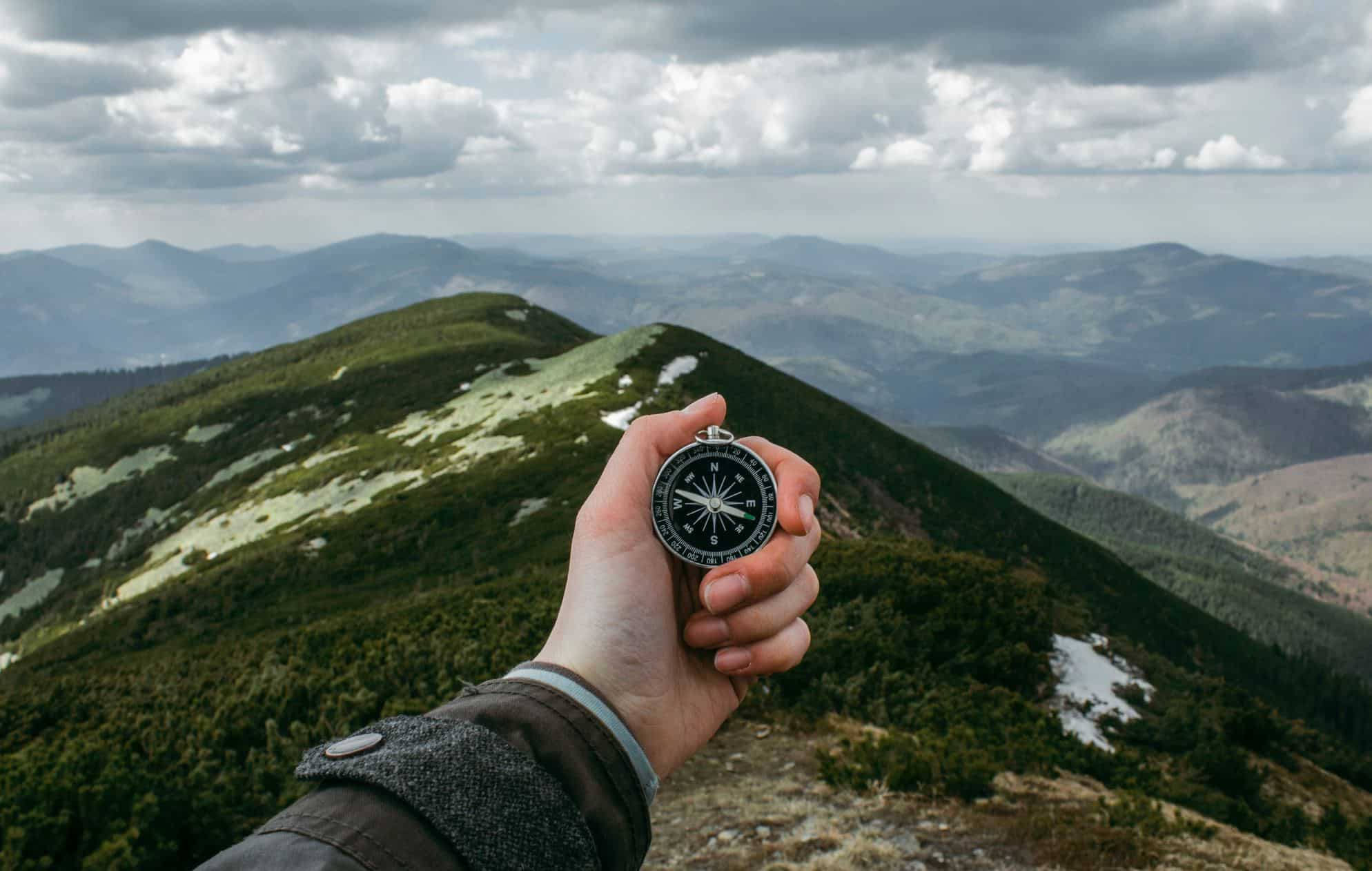main tendue avec boussole sur une destination montagneuse